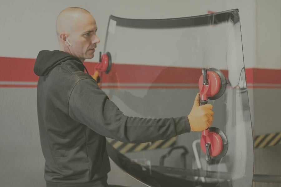 Technician carrying a windshield with suction handles